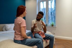 Two people sitting on a bed talking