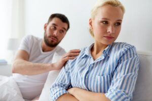 Two people are sitting on a bed in front of each other.