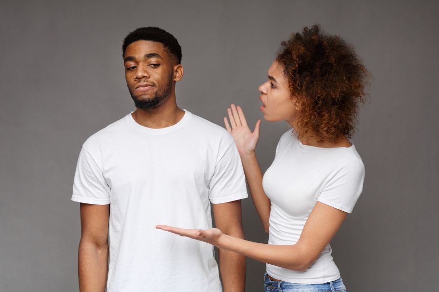 A woman is talking to a man in a white t-shirt