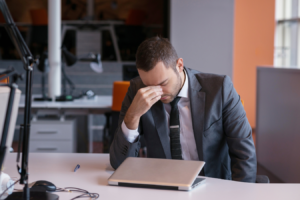 a person in a suit sitting at a desk with their head in their hands