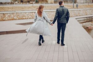 Two people walking on a boardwalk holding hands
