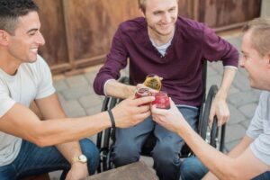 three individuals in wheelchairs are toasting each other