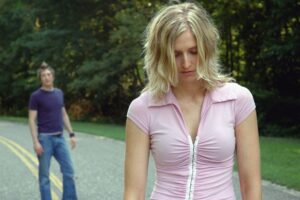 A man looking at woman from behind walking away unhappy.