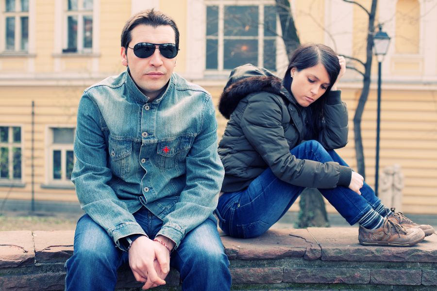 Two people sitting on a bench in front of a building