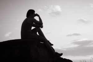 silhouette of a person sitting on top of a rock