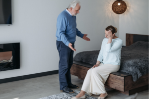 an older man and woman standing in front of a bed