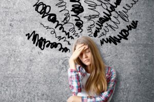 a person is holding their head in their hands while standing in front of a wall with many words written on it