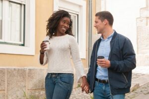 Two people holding hands while walking down the street